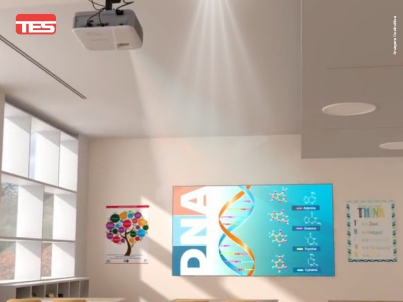 a imagem mostra uma sala de aula com uma grande tela de projeção exibindo informações sobre dna. na parede, há um cartaz com ilustrações coloridas representando uma árvore da vida, provavelmente usado como material didático. também há um quadro de avisos com anotações e símbolos, possivelmente para chamar a atenção dos alunos.